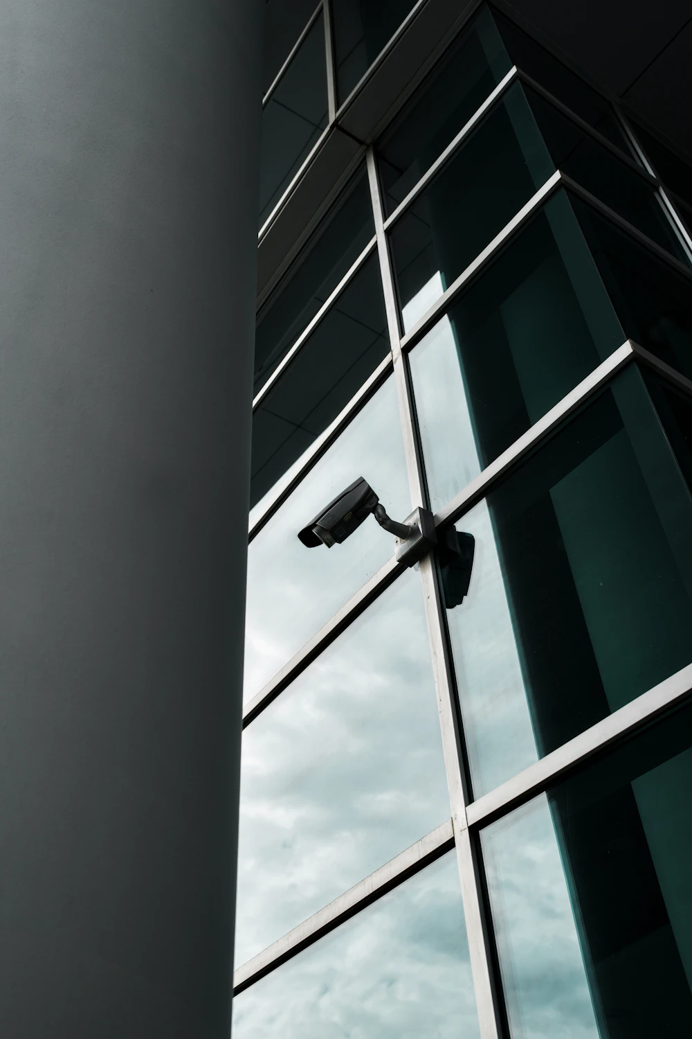 Cámara de vigilancia sobre una fachada de vidrio, vista en diagonal como fotografía de referencia